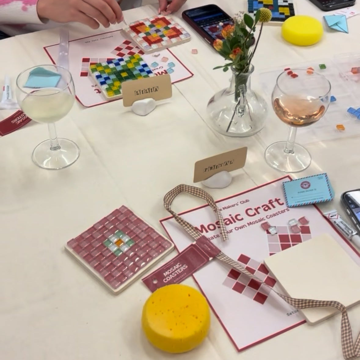Two people engaged in a mosaic craft activity at a table with materials and instructions.